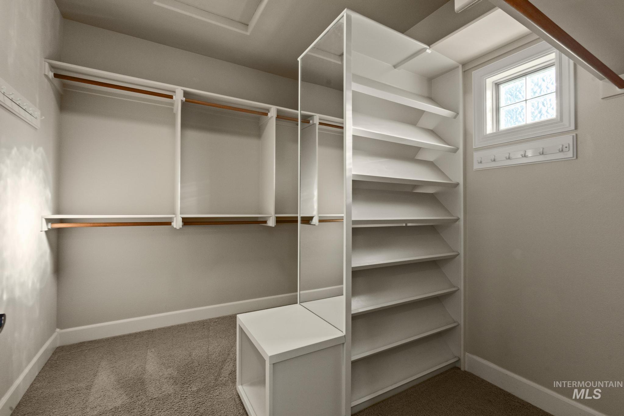 4946 North Villa Ridge Way Boise, ID 83703 - Photo 25 of 49 Built-in closet system featuring multiple hanging rods, white shelving units, a white storage cube, a window with obscure glass, and a wall-mounted hook rack