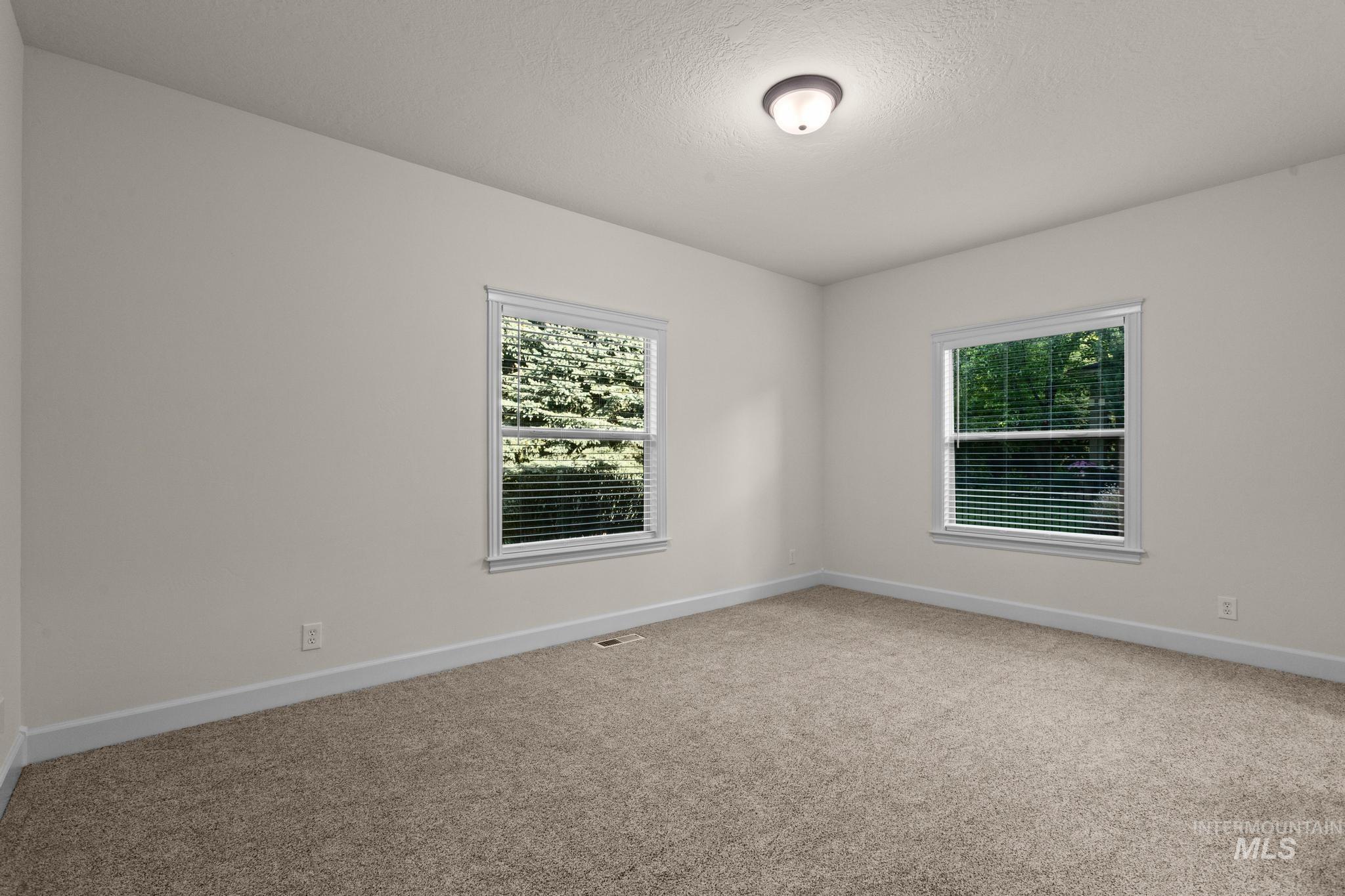 4946 North Villa Ridge Way Boise, ID 83703 - Photo 29 of 49 Room featuring light neutral wall paint, two windows with white blinds, and textured carpet flooring