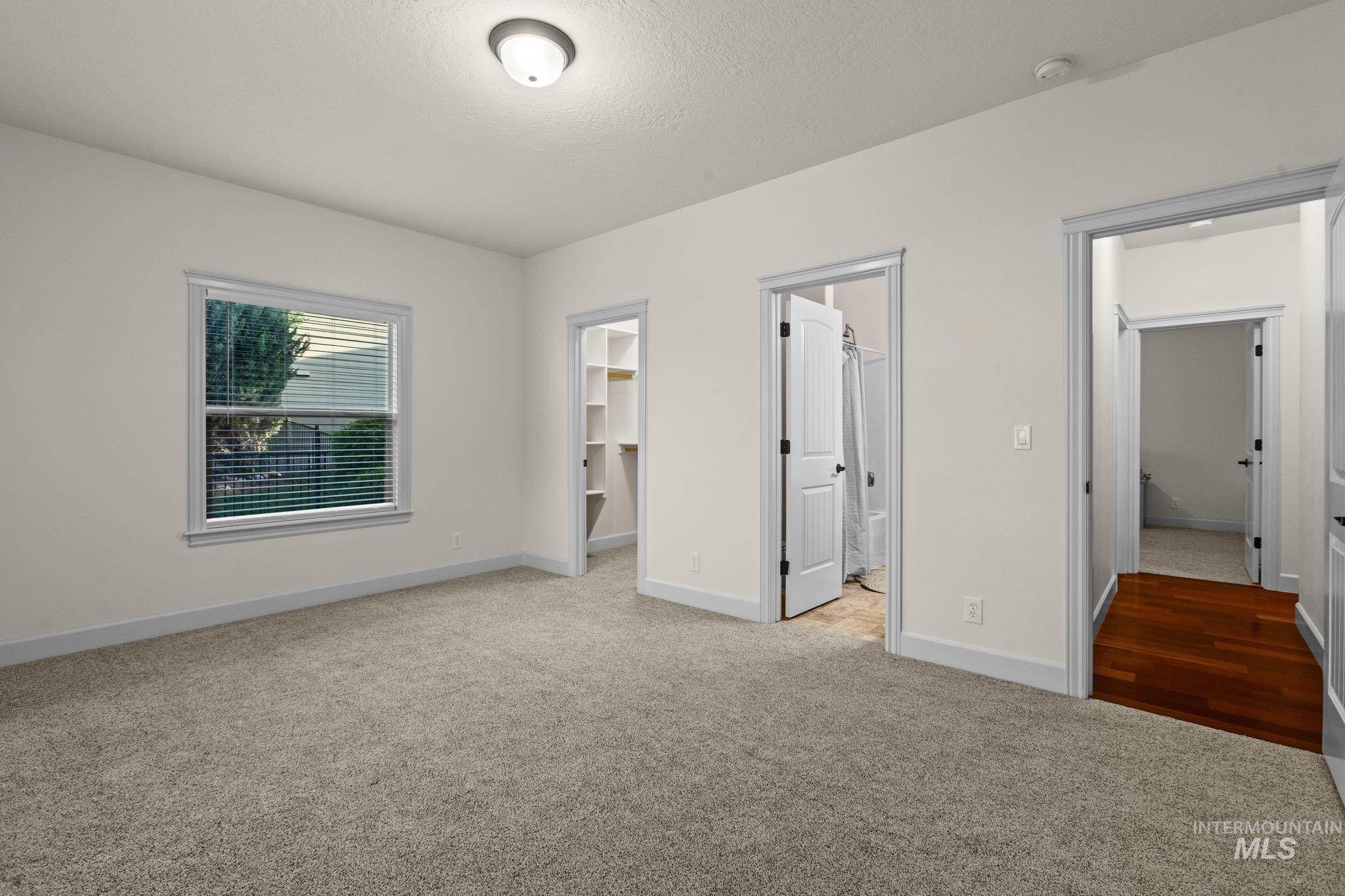 4946 North Villa Ridge Way Boise, ID 83703 - Photo 30 of 49 Carpeted room featuring a window with blinds, a ceiling-mounted light fixture, a walk-in closet with shelving, and access to a bathroom with a shower