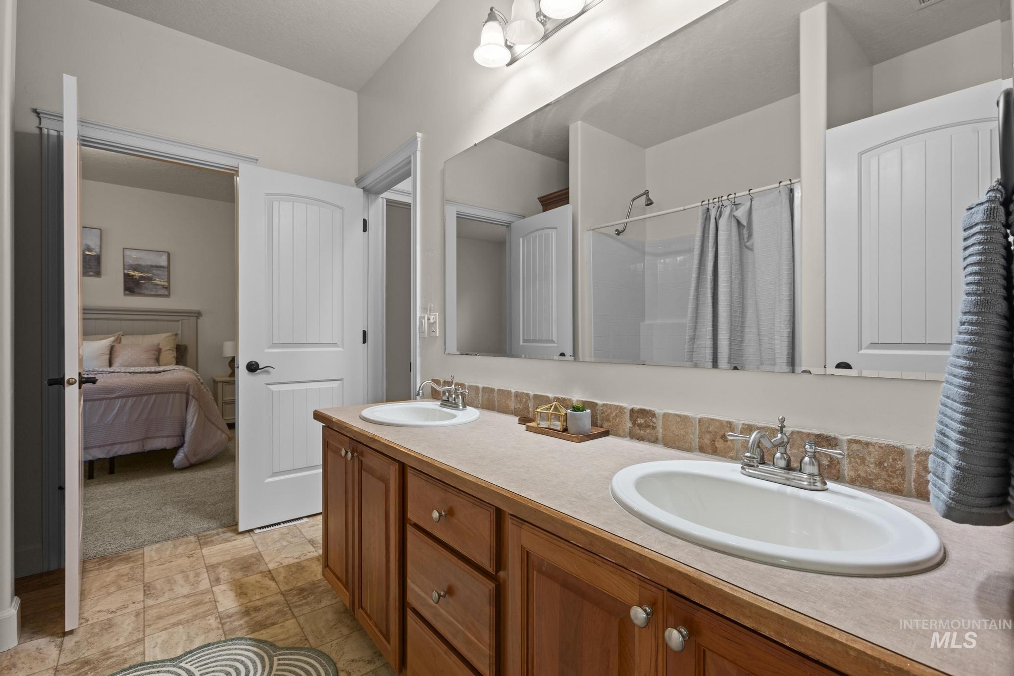 4946 North Villa Ridge Way Boise, ID 83703 - Photo 32 of 49 Double vanity with wood-finish cabinetry, oval undermount sinks, and a tiled backsplash