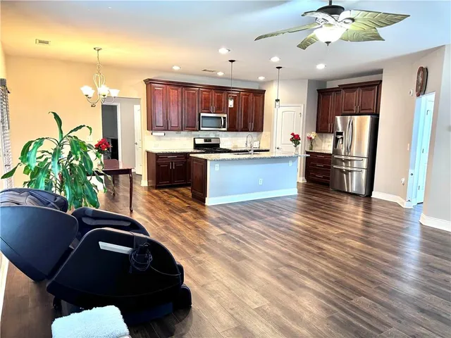 a kitchen with kitchen island granite countertop wooden cabinets stainless steel appliances and a window