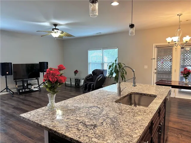 a kitchen with kitchen island granite countertop a sink appliances and wooden floor