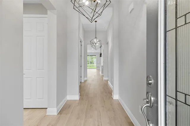 a view of a hallway with wooden floor and chandelier
