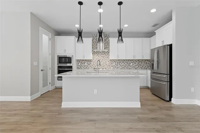 a kitchen with white cabinets and sink