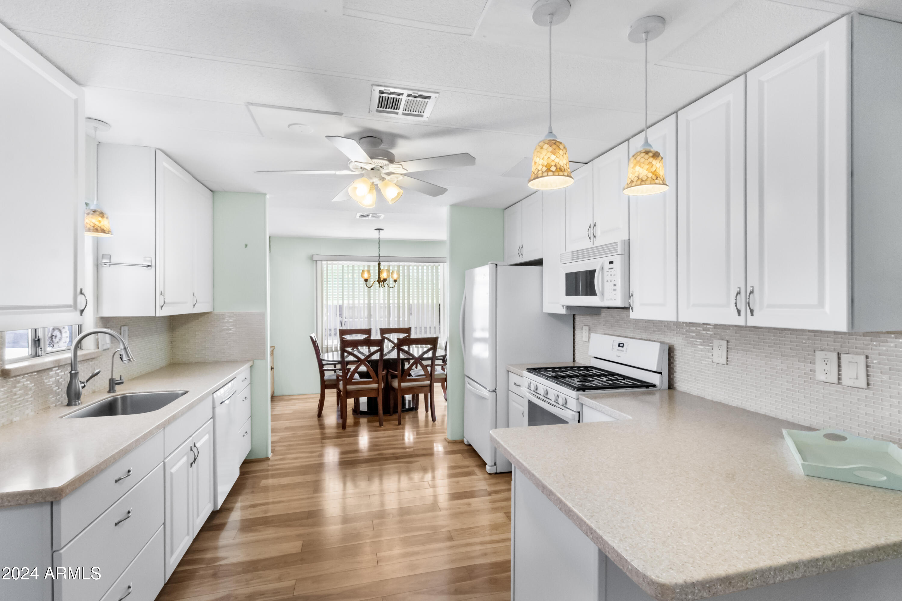 a kitchen with stainless steel appliances granite countertop a stove top oven a sink a dining table and chairs with white cabinets