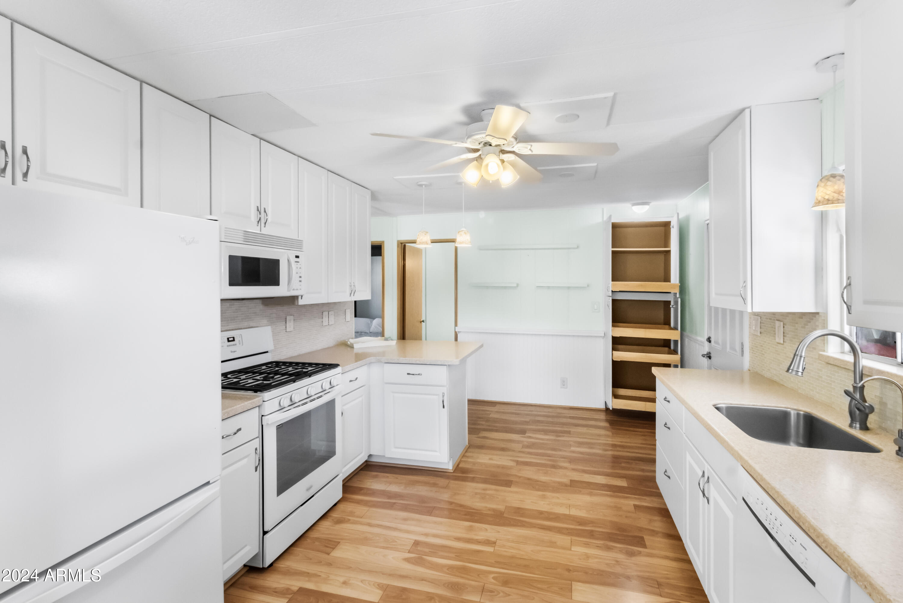 2100 North Trekell Road, Unit 204 Casa Grande, AZ 85122 - Photo 12 of 27 a large kitchen with stainless steel appliances a stove a sink dishwasher a refrigerator white cabinets and wooden floor