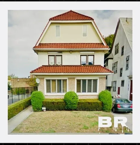 a view of a white house with a large windows and a yard