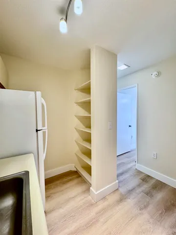 a view of empty room with wooden floor and fan