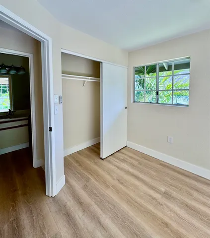 an empty room with wooden floor a ceiling fan and windows