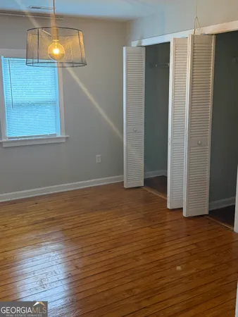 a view of an empty room with wooden floor and chandelier