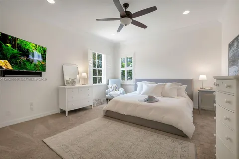 a bedroom with a large bed and a flat tv screen on dresser