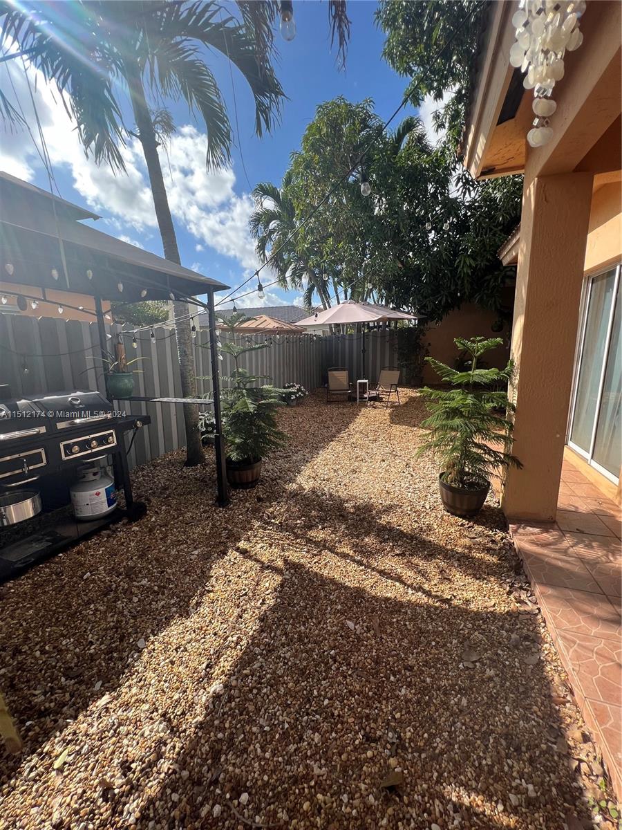 8118 Northwest 200th Street Hialeah, FL 33015 - Photo 22 of 24 a view of a backyard with table and chairs under an umbrella with large trees