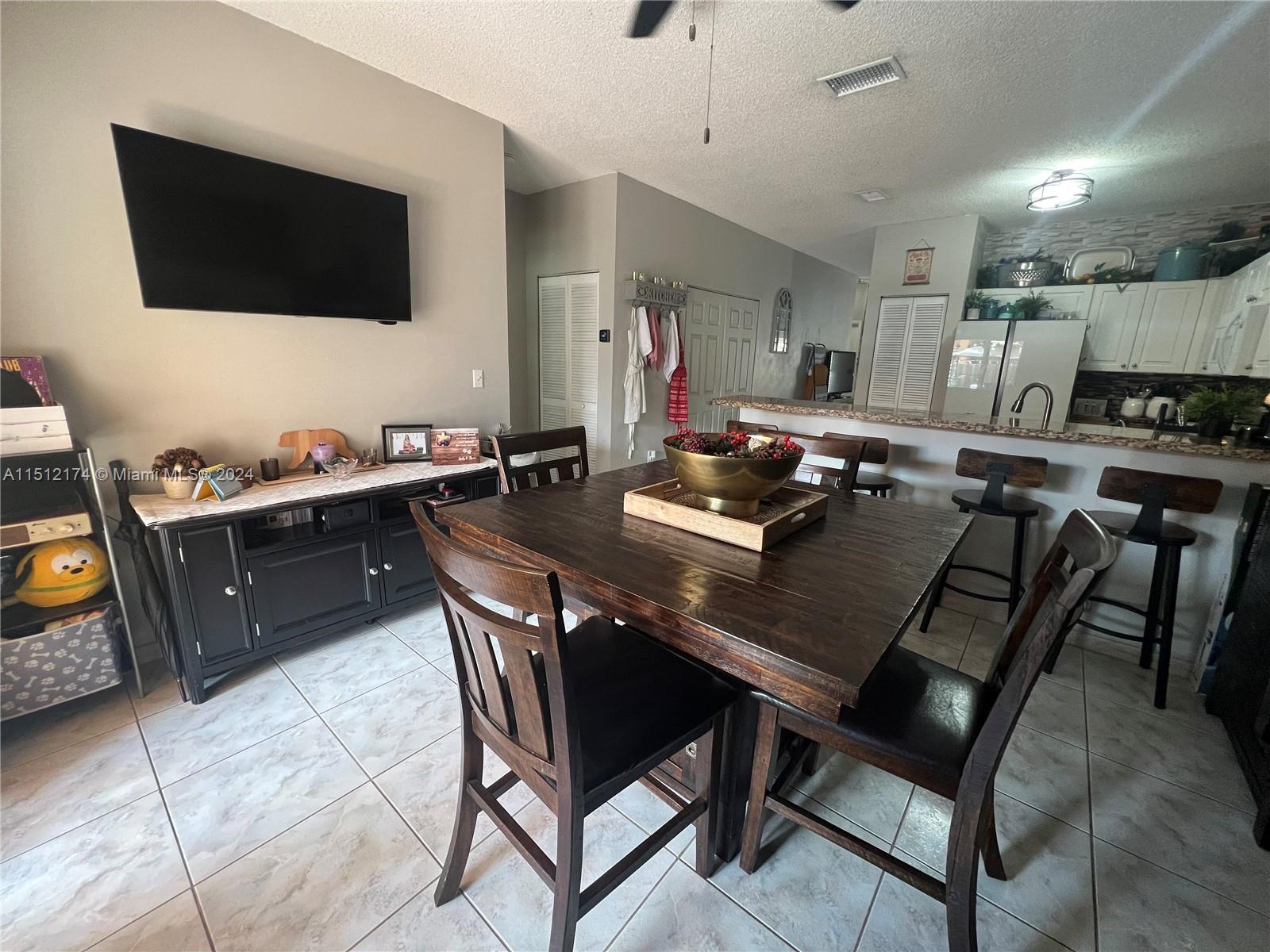 8118 Northwest 200th Street Hialeah, FL 33015 - Photo 8 of 24 a living room with furniture a flat screen tv and kitchen view
