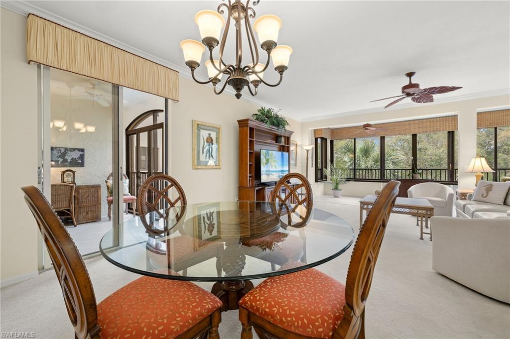6500 Valen Way, Unit A203 Naples, FL 34108 - Photo 2 of 18 Dining room featuring ceiling fan with notable chandelier, crown molding, and light colored carpet