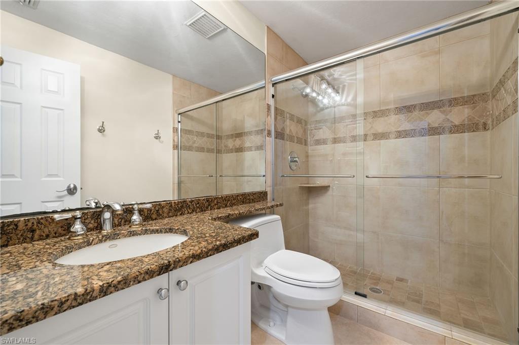 6500 Valen Way, Unit A203 Naples, FL 34108 - Photo 10 of 18 Bathroom with vanity, toilet, visible vents, and a stall shower
