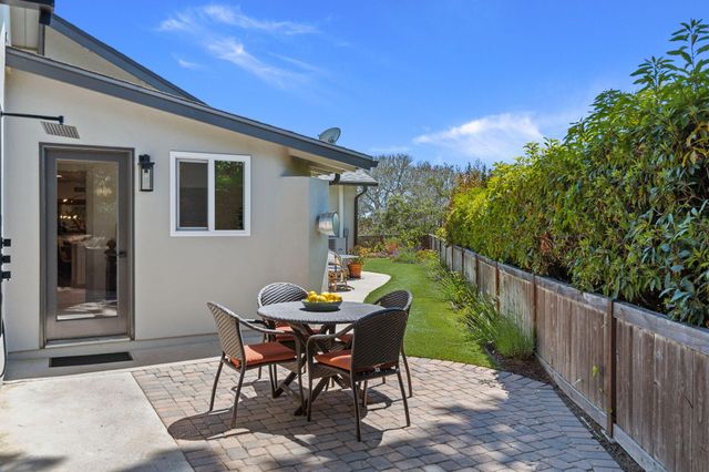 a view of a patio with a table and chairs and a floor to ceiling window with wooden fence