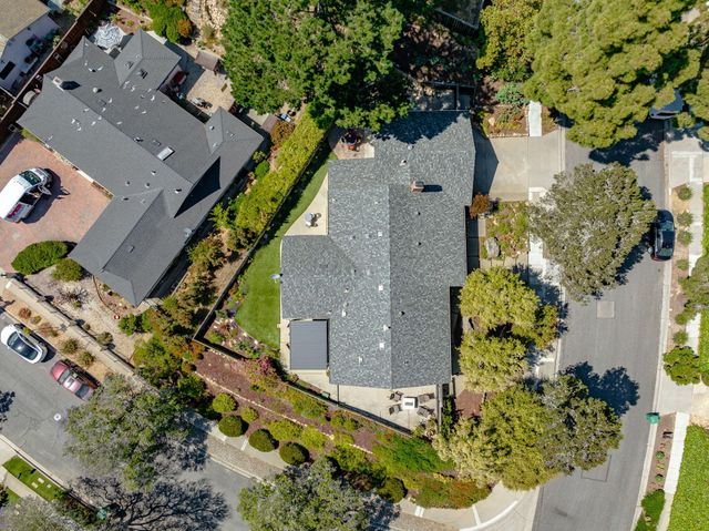 an aerial view of a house with a yard and trees all around