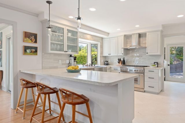 a kitchen with stainless steel appliances kitchen island granite countertop a table chairs sink and cabinets