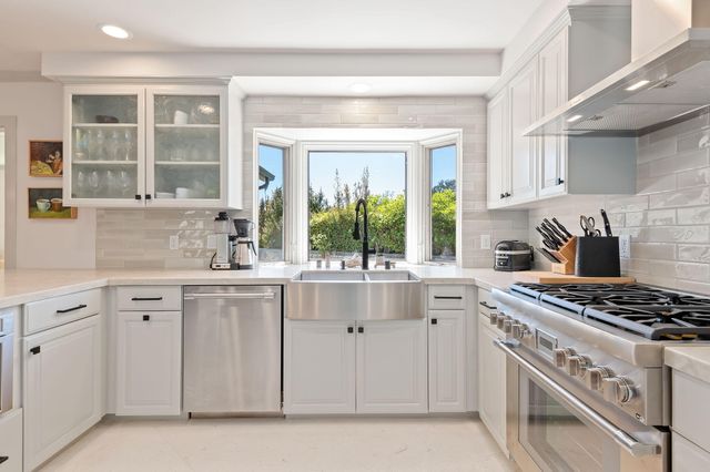 a kitchen with white cabinets and a stove top oven
