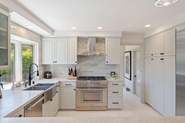 a kitchen with stainless steel appliances white cabinets and a stove top oven