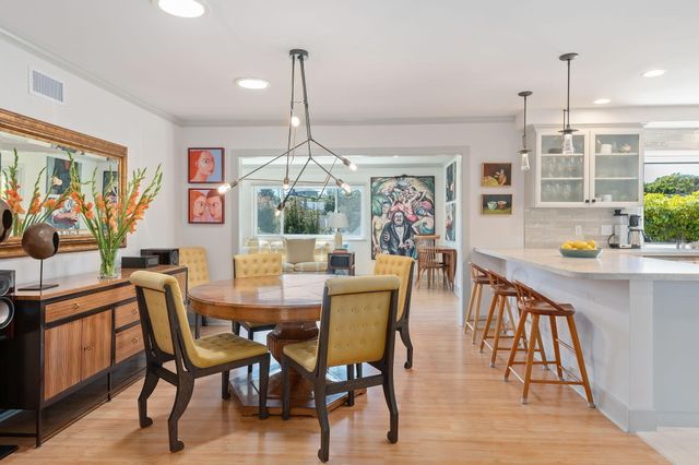 a view of a dining room and livingroom with furniture wooden floor a rug a painting and a chandelier