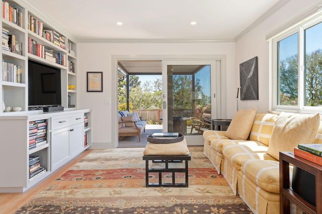 a living room with furniture a flat screen tv and floor to ceiling window