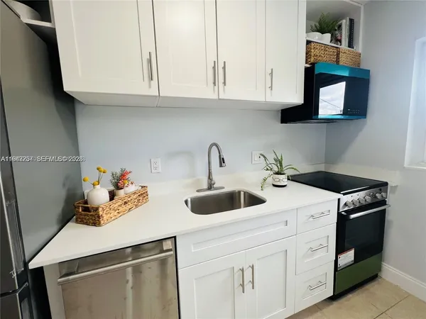a kitchen with white cabinets and sink
