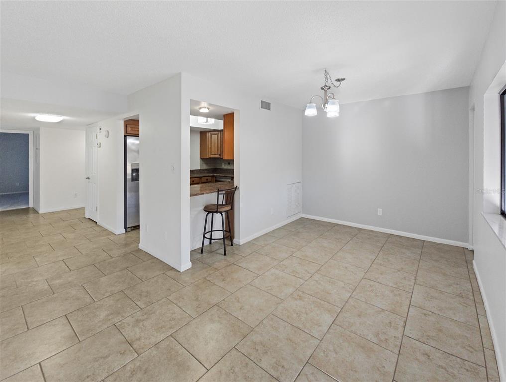 680 Midway Drive, Unit A Ocala, FL 34472 - Photo 8 of 39 an empty room with kitchen and chandelier fan
