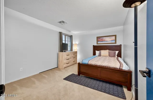 a bedroom with a bed and a lamp on dresser