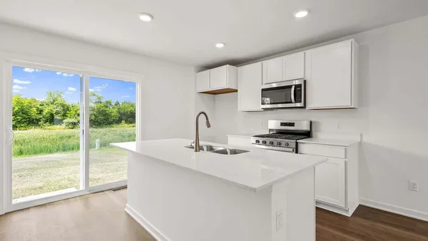 a kitchen with stainless steel appliances granite countertop a stove a sink a microwave a refrigerator and white cabinets with wooden floor