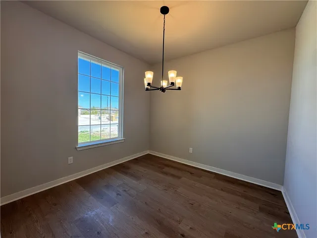 a view of a room with wooden floor chandelier and window