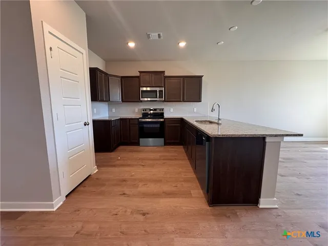 a large kitchen with stainless steel appliances kitchen island granite countertop a refrigerator and a stove top oven