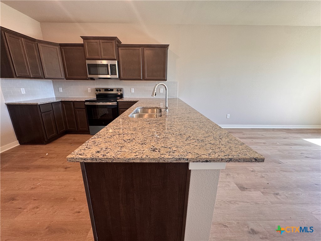 409 University Avenue Troy, TX 76579 - Photo 8 of 20 a kitchen with kitchen island granite countertop a stove top oven a sink and dishwasher
