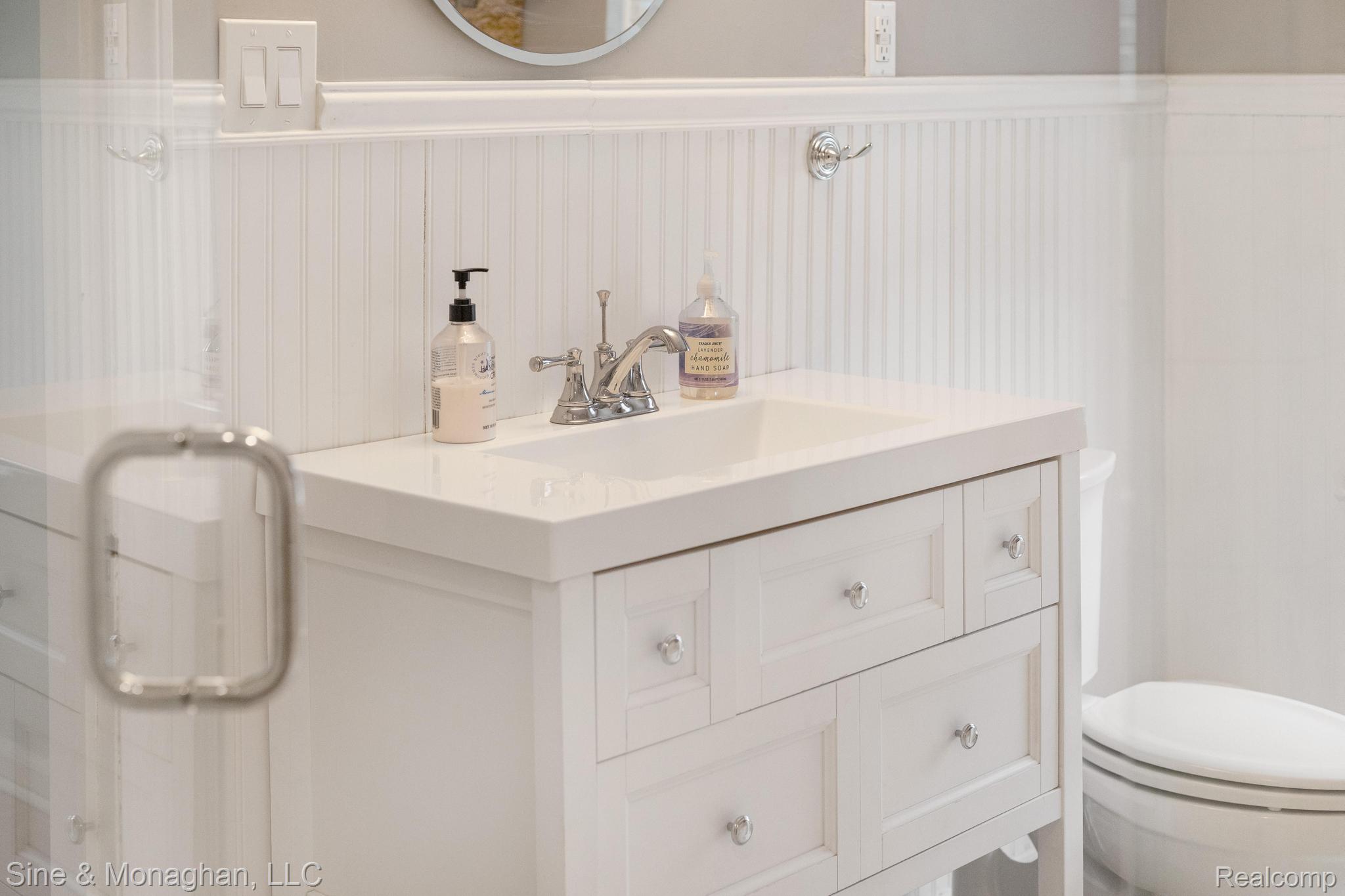 679 Neff Road Grosse Pointe, MI 48230 - Photo 25 of 78 White vanity with integrated sink, chrome faucet, beadboard wainscoting, and polished knob hardware