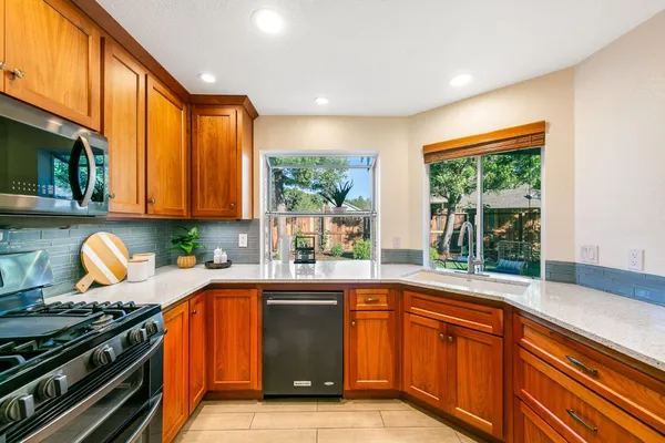 a kitchen with stainless steel appliances granite countertop a stove a sink and a microwave