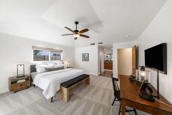 a bedroom with a bed a flat screen tv and a chandelier