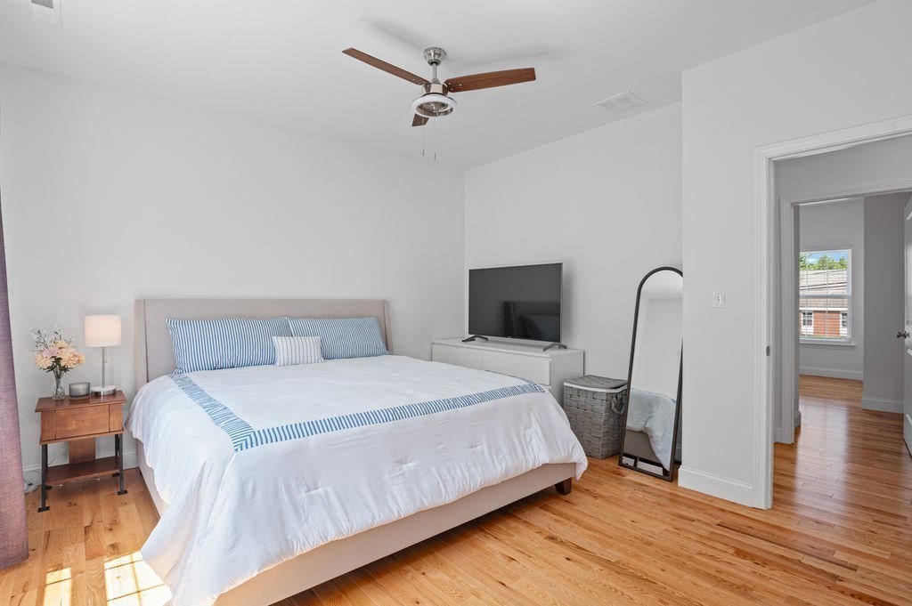 196 Main Street, Unit 196 Groveland, MA 01834 - Photo 13 of 35 a bedroom with a bed a dresser and wooden floor