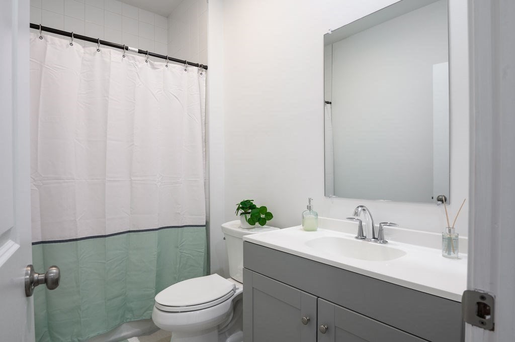 196 Main Street, Unit 196 Groveland, MA 01834 - Photo 18 of 35 a bathroom with a sink a toilet a mirror and shower curtain