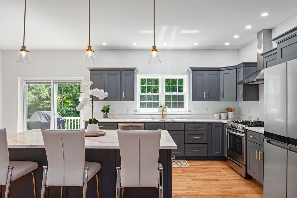196 Main Street, Unit 196 Groveland, MA 01834 - Photo 5 of 35 a kitchen with stainless steel appliances granite countertop a stove a sink dishwasher a refrigerator white cabinets wooden floor and a dining table