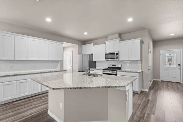 a kitchen with stainless steel appliances granite countertop a sink stove refrigerator and cabinets