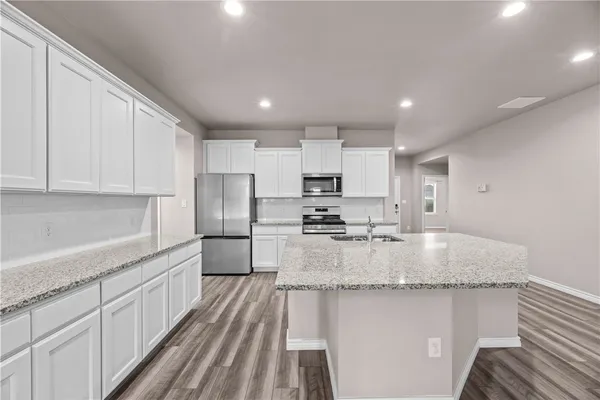 a kitchen with kitchen island granite countertop a sink stove and refrigerator