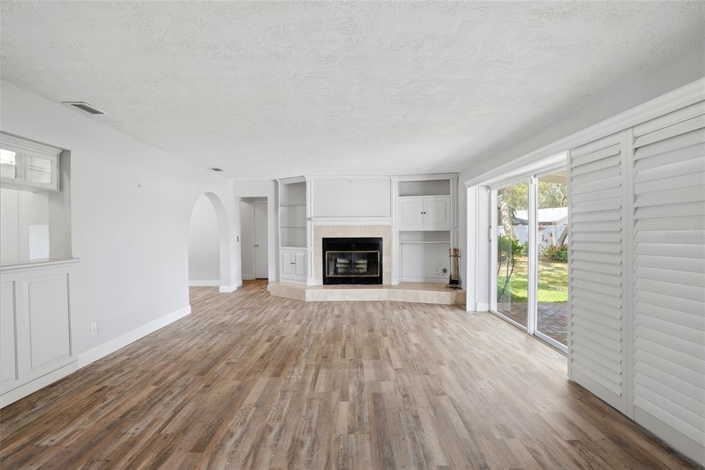 9760 136th Street Seminole, FL 33776 - Photo 19 of 41 a view of an empty room with wooden floor fireplace and a window