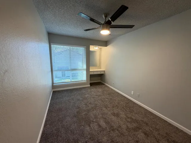 an empty room with closet and a ceiling fan