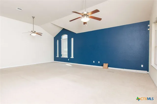 an empty room with windows and fan