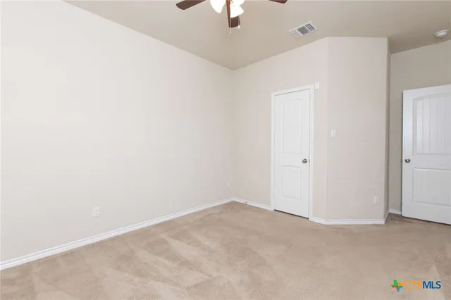 an empty room with a ceiling fan and window