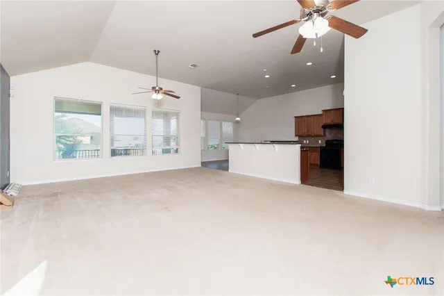 an empty room with windows and ceiling fan