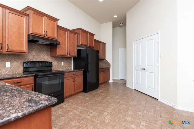 a kitchen with stainless steel appliances granite countertop a refrigerator stove and a sink