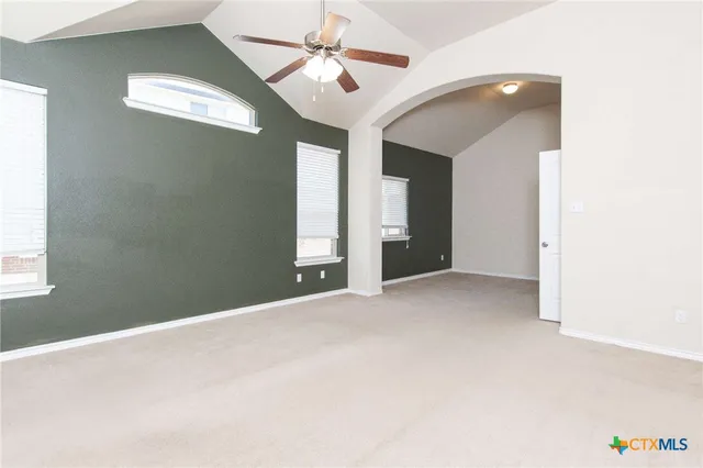 a view of a big room with windows and ceiling fan