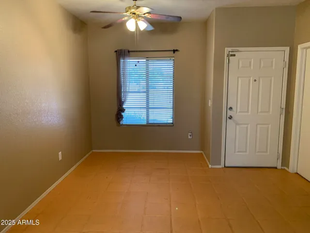 an empty room with a chandelier fan and windows