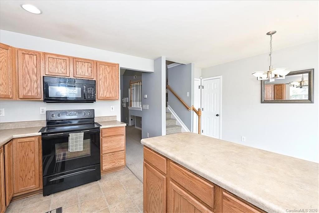 231 Primrose Walk Fort Mill, SC 29715 - Photo 17 of 34 a kitchen with stainless steel appliances kitchen island granite countertop a stove a sink and a microwave